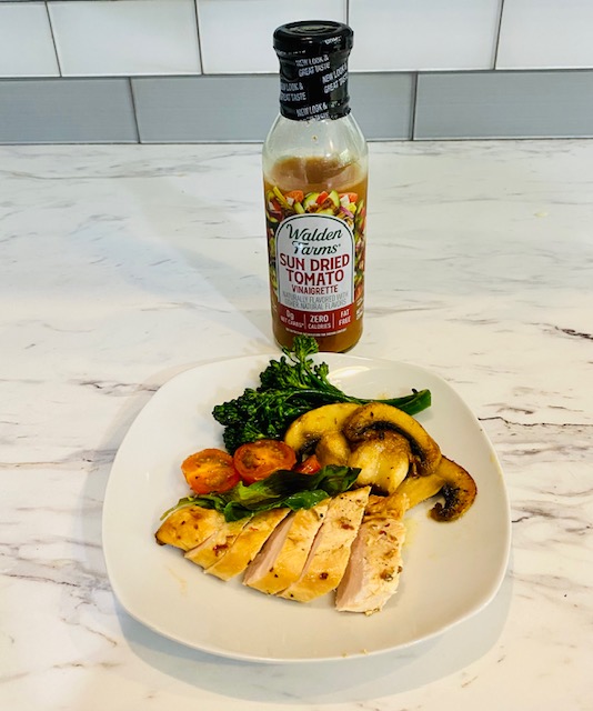 Walden Farms Sun-Dried Tomato Vinaigrette next to grilled chicken and veggies on a plate