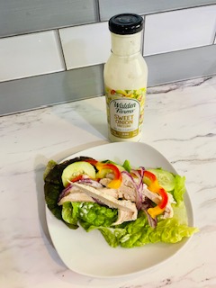 sweet onion dressing next to chicken lettuce wrap on plate